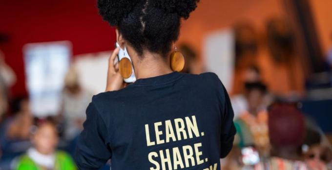 woman from behind in a shirt that reads learn, share, transform